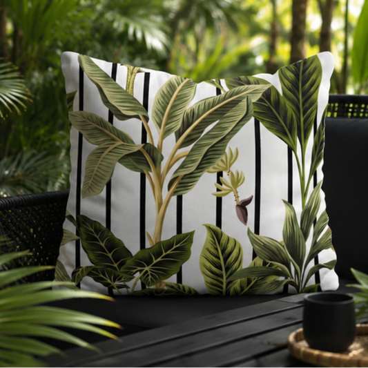 Tropical leaf cushion cover with green botanical design over black and white striped background
