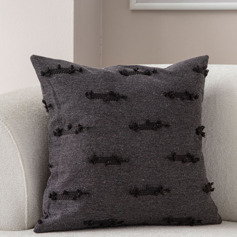 Dark charcoal textured woven throw pillow on light sofa – decorative cushion with horizontal tufted accents