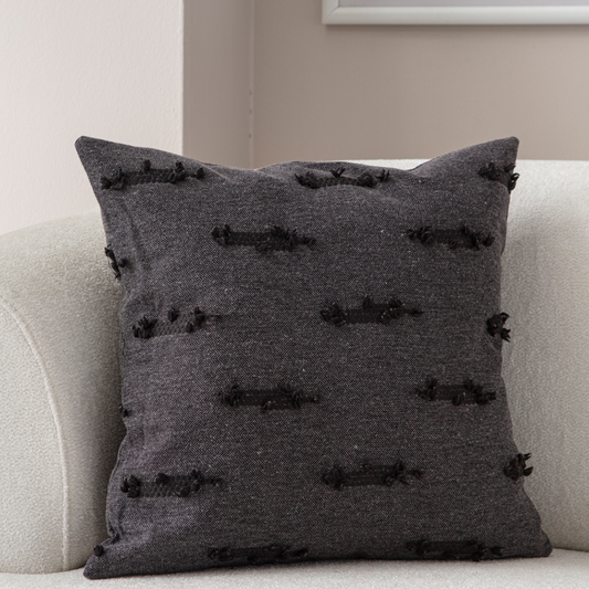 Dark charcoal textured woven throw pillow on light sofa – decorative cushion with horizontal tufted accents