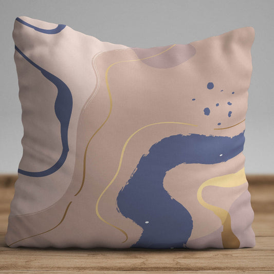 Warm neutral cushion cover with abstract shapes in beige, blue, and gold tones on a decorative pillow