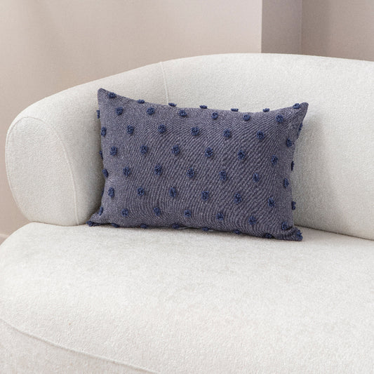 Blue textured cushion with raised knot-dot details placed on a light beige sofa.