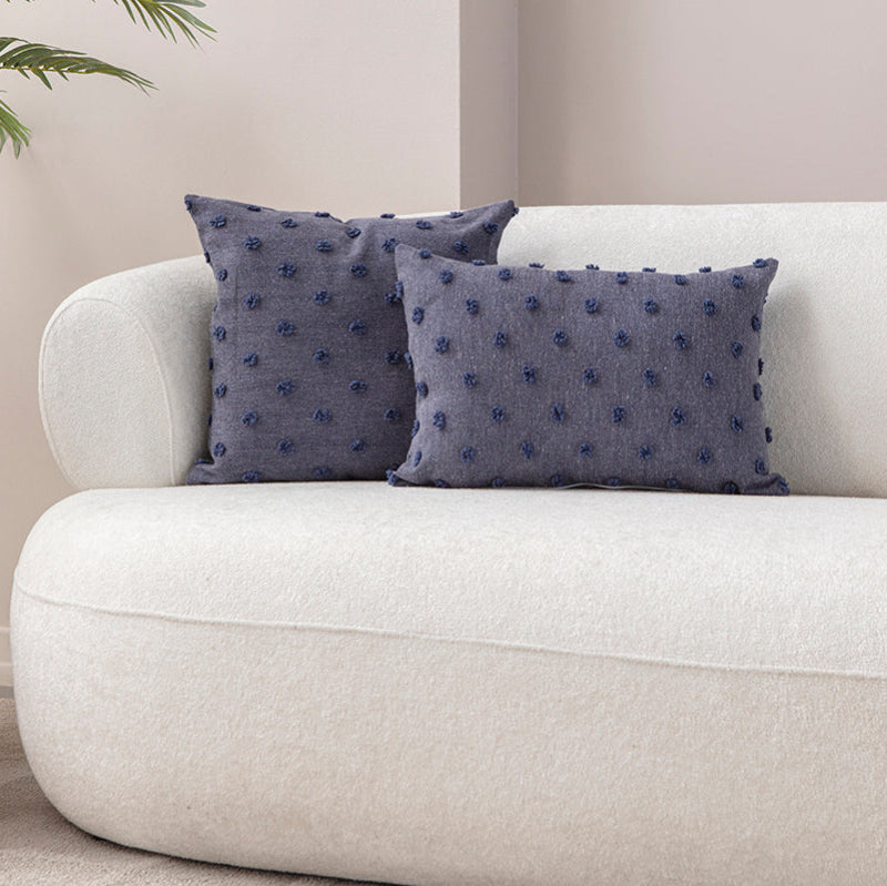 Blue textured cushion with raised knot-dot details placed on a light beige sofa.