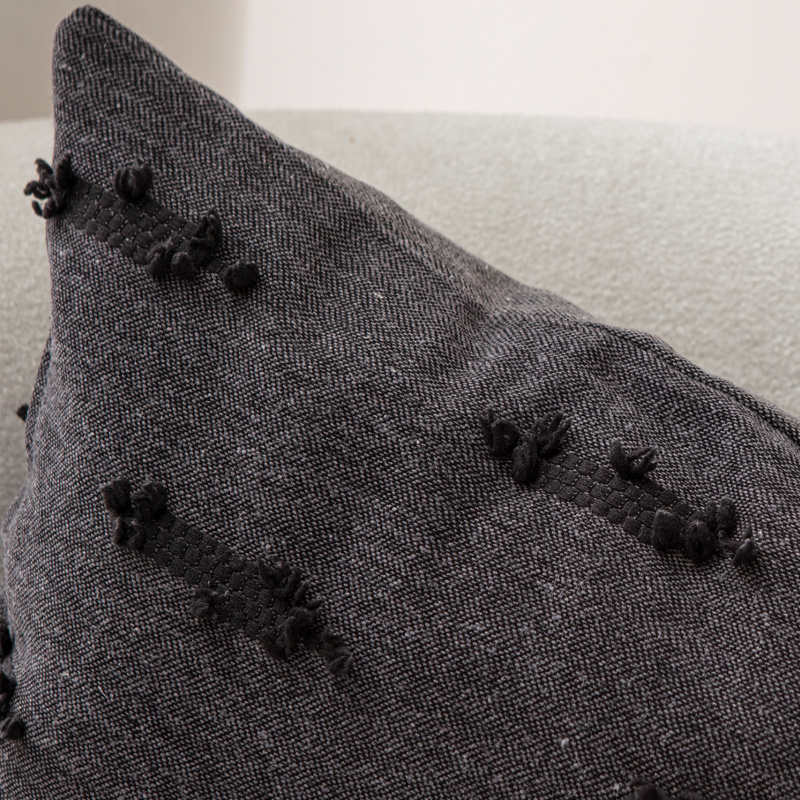 Dark charcoal textured woven throw pillow on light sofa – decorative cushion with horizontal tufted accents