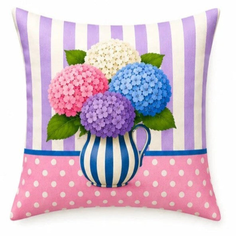 Set of four pastel hydrangea decorative cushion covers featuring floral bouquets, striped ceramic vases, gingham backgrounds, and soft yellow, pink, lavender, and blue accents displayed on a cozy armchair.