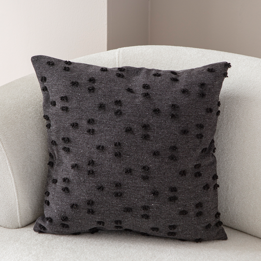 Dark charcoal tufted throw pillow on light sofa – textured decorative cushion