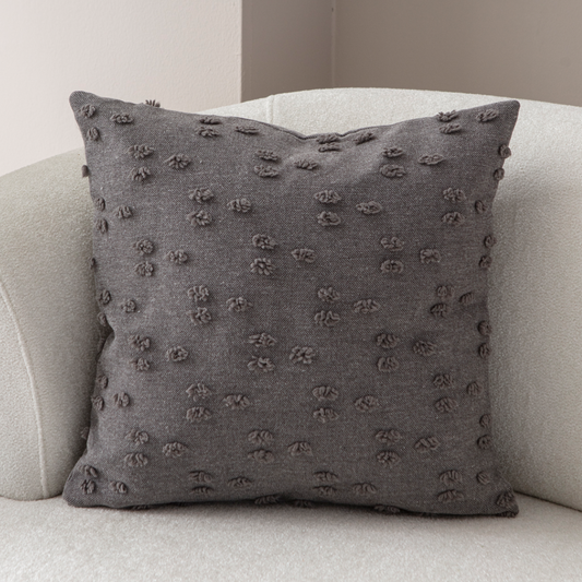 Charcoal textured tufted throw pillow on light sofa – modern decorative cushion