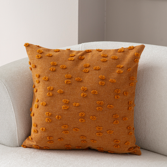 Burnt orange tufted throw pillow on light sofa – textured decorative cushion