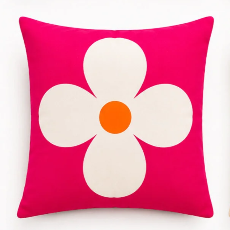 Set of four vibrant tropical decorative cushion covers featuring a cheetah illustration, abstract coral waves, bold white floral artwork, and a palm tree design displayed on a modern white sofa in a lush garden setting.