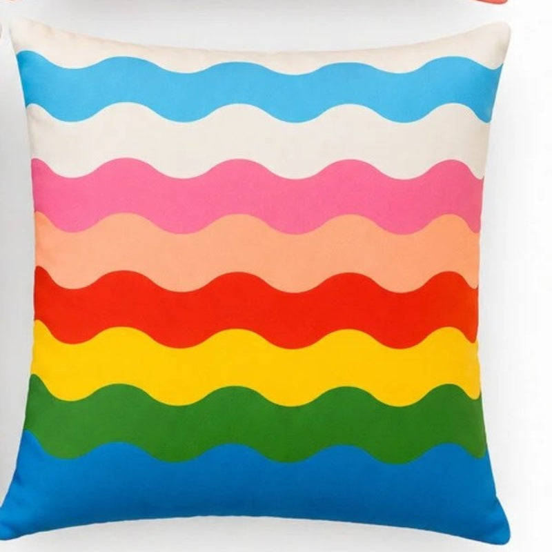 Set of four colorful Mediterranean-inspired decorative cushion covers featuring "La Dolce Vita" typography, floral ceramic planters, striped backgrounds, and a vibrant rainbow wave pattern displayed on a modern cream sofa.