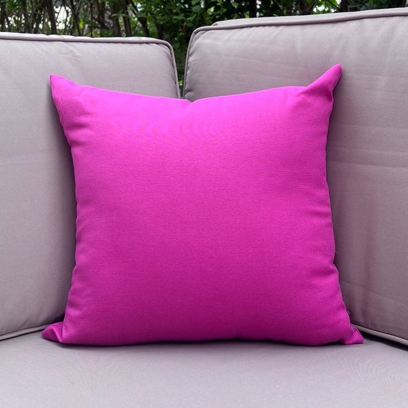 Fusia cushion cover displayed on a beige outdoor sofa in a garden patio setting