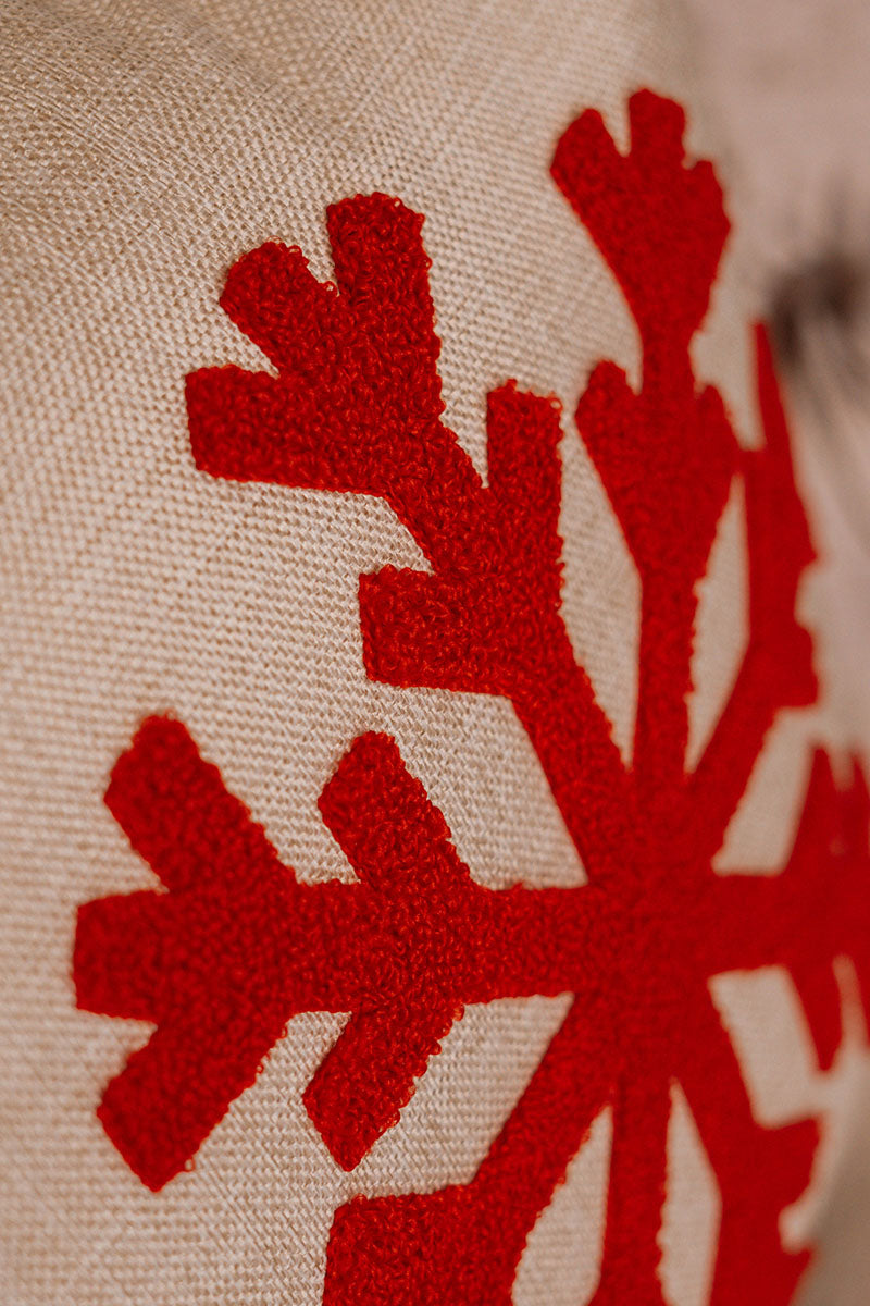 Beige cushion with embroidered red snowflake on a blue sofa – Autumn Bloom Collection
