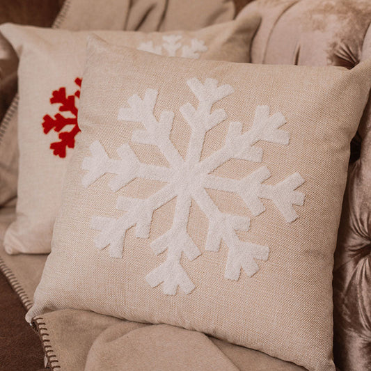 Beige cushion with raised white snowflake embroidery on a blue sofa – Autumn Bloom Collection