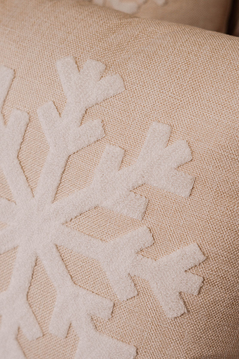 Beige cushion with raised white snowflake embroidery on a blue sofa – Autumn Bloom Collection