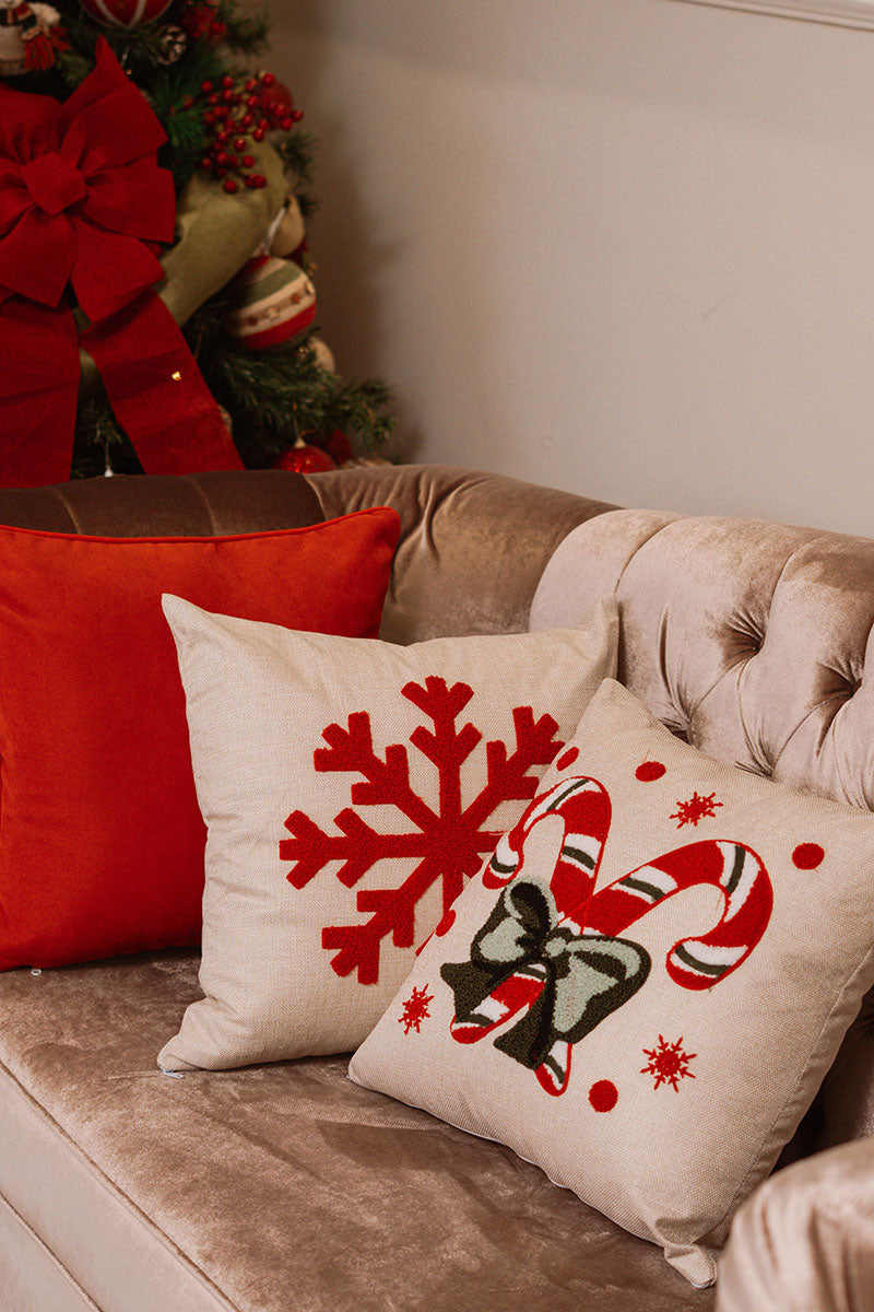Beige cushion with embroidered red and white candy canes tied with a green bow on a blue sofa – Autumn Bloom Collection