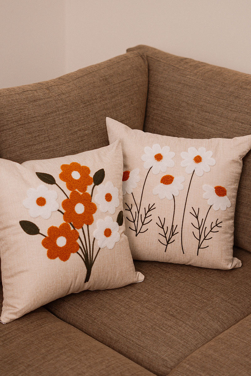 Beige cushion with embroidered bouquet of orange and white flowers on a blue sofa – Autumn Bloom Collection