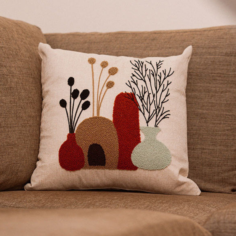 Beige cushion with embroidered terracotta and green vases filled with foliage on a blue sofa – Autumn Bloom Collection