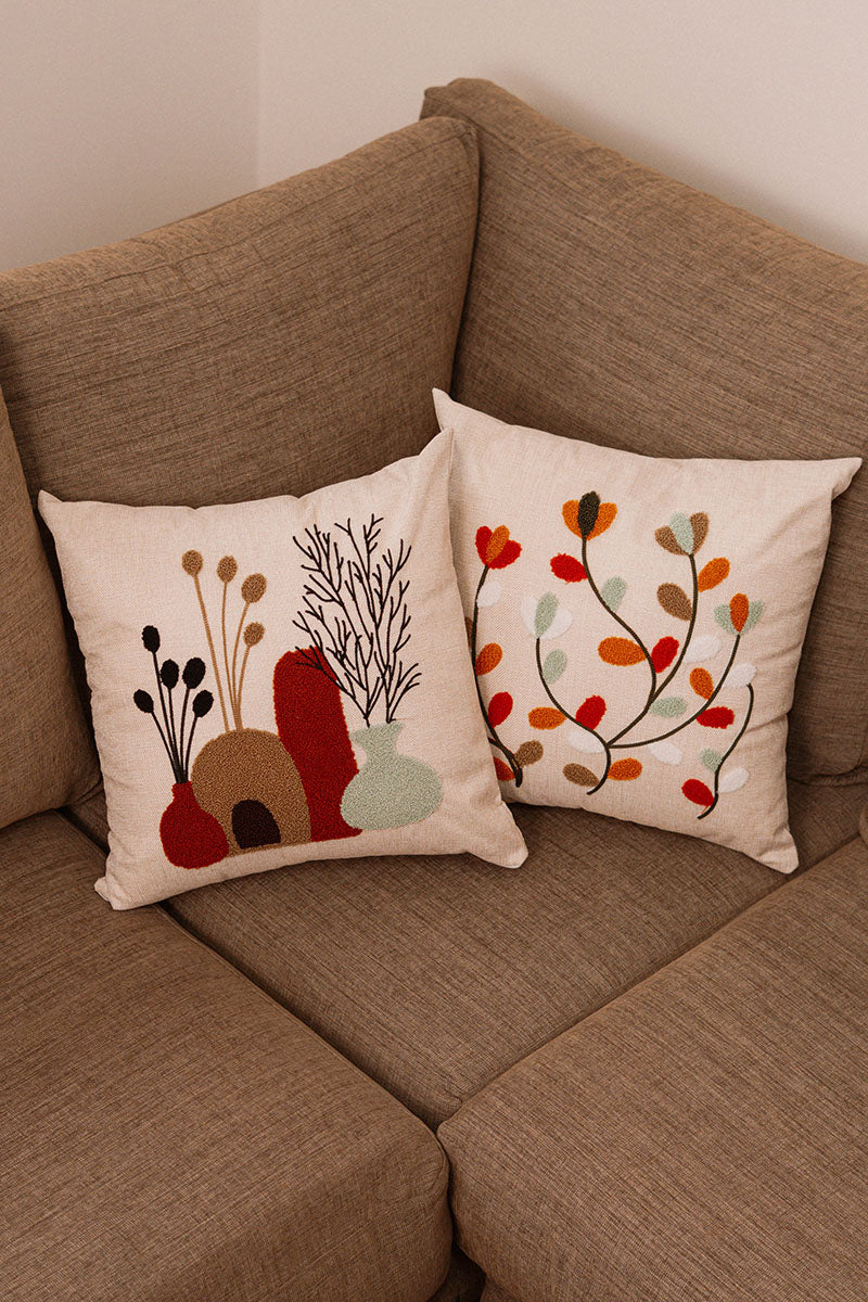 Beige cushion with embroidered terracotta and green vases filled with foliage on a blue sofa – Autumn Bloom Collection
