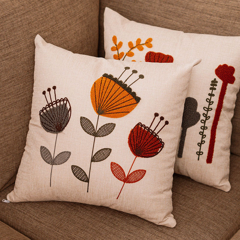 Embroidered floral cushion cover in beige fabric with colorful boho flowers on a blue sofa