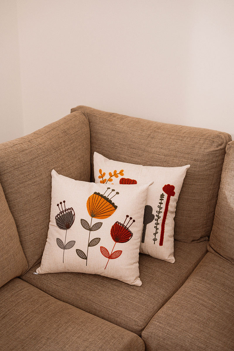 Beige cushion with multicolor embroidered flowers on a blue velvet sofa – Autumn Bloom Collection