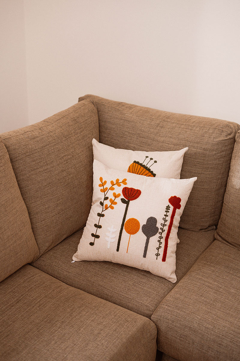 Beige cushion with multicolor embroidered flowers on a blue velvet sofa – Autumn Bloom Collection