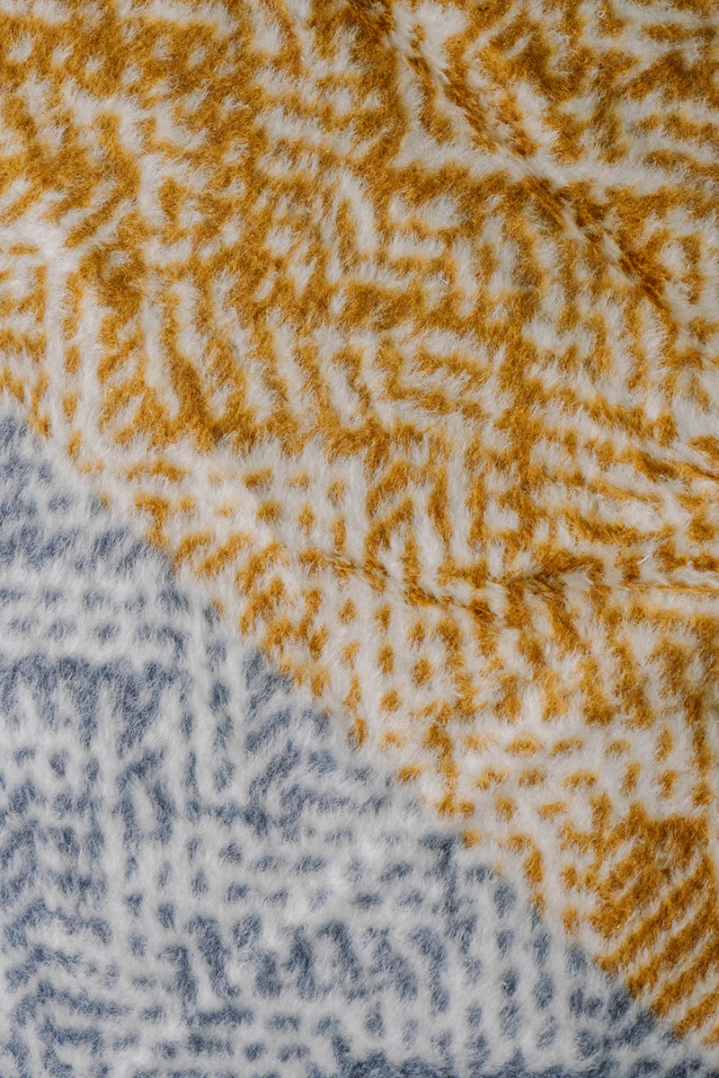 Multicolor chevron fleece blanket in yellow, purple, pink, and grey on sofa