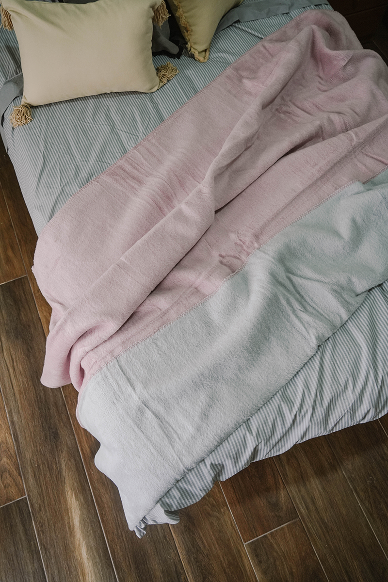 Double-face fleece blanket in pink and grey draped on chair