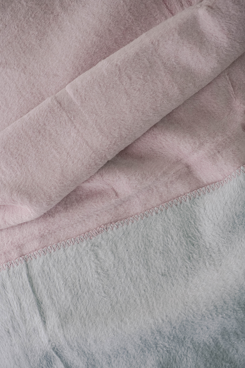 Double-face fleece blanket in pink and grey draped on chair