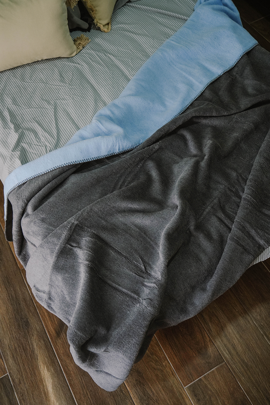 Double-face fleece blanket in pink and grey draped on chair