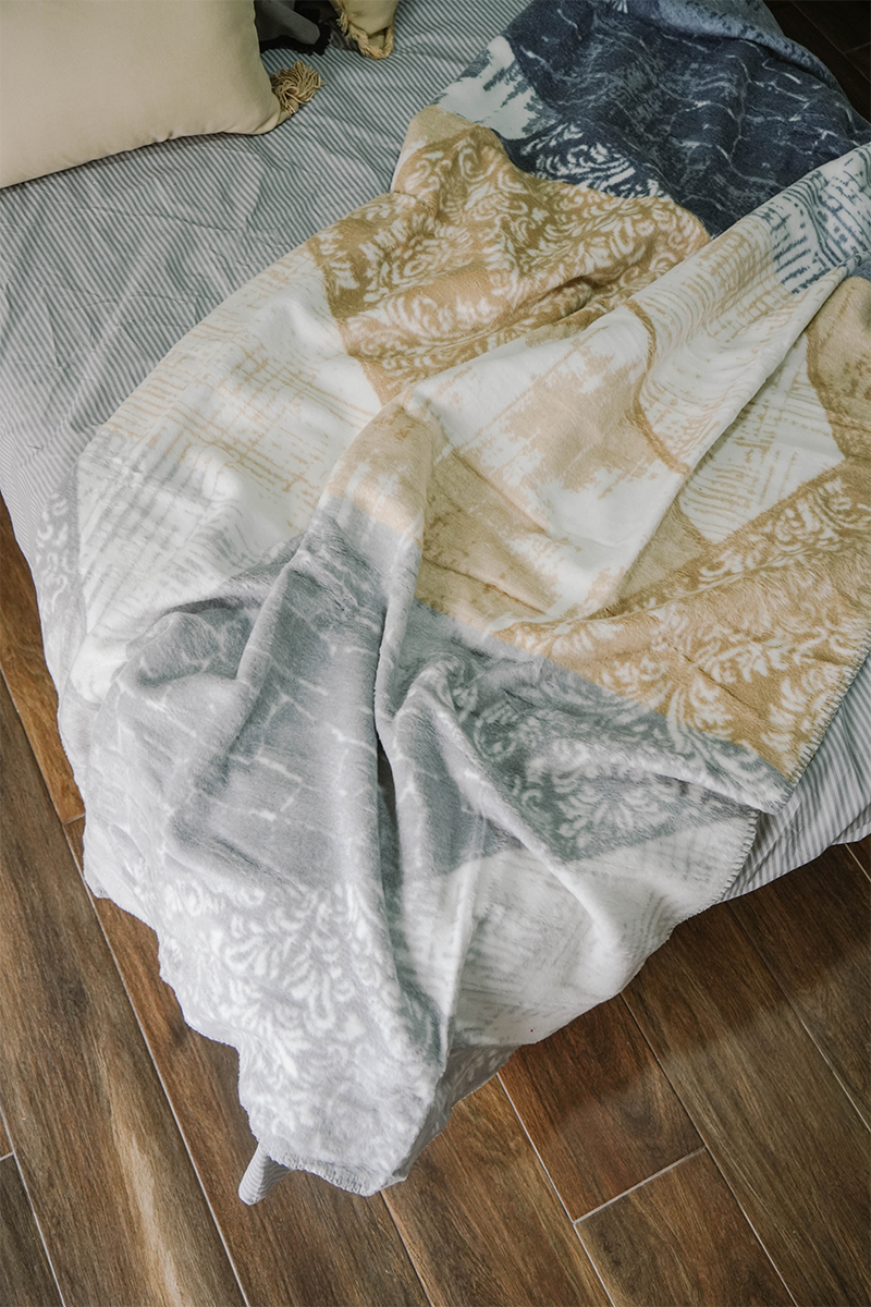 Geometric beige and grey fleece blanket draped on wooden rod