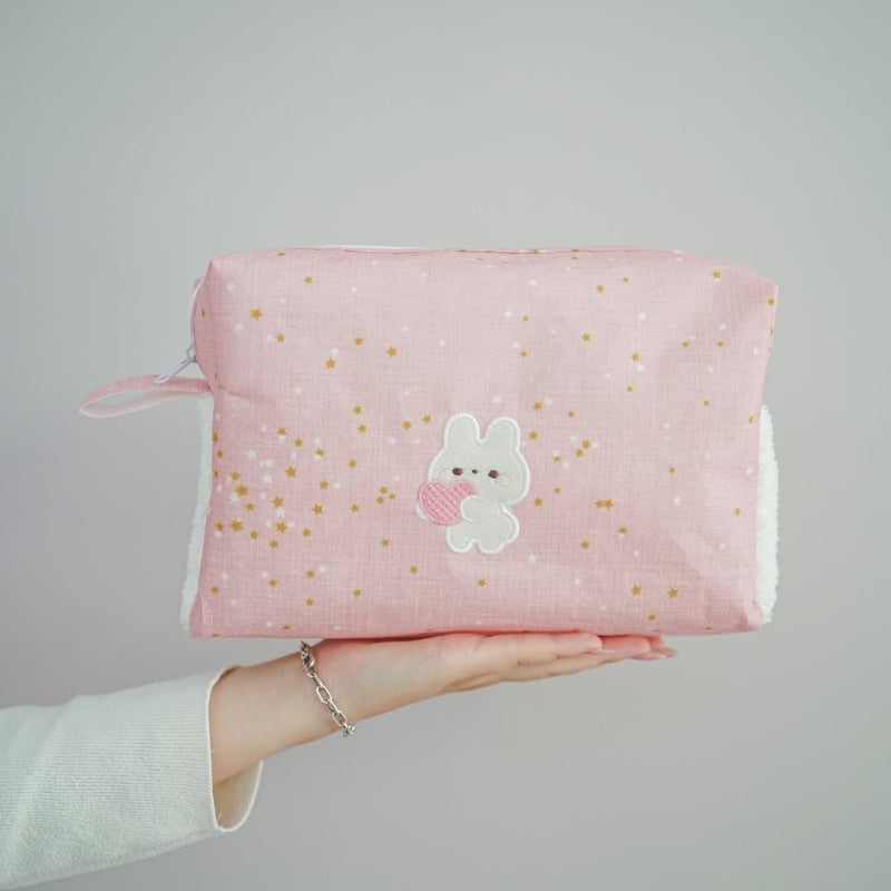 Pink baby nursery organizer set with decorative tissue box cover and zippered storage pouch placed on bed