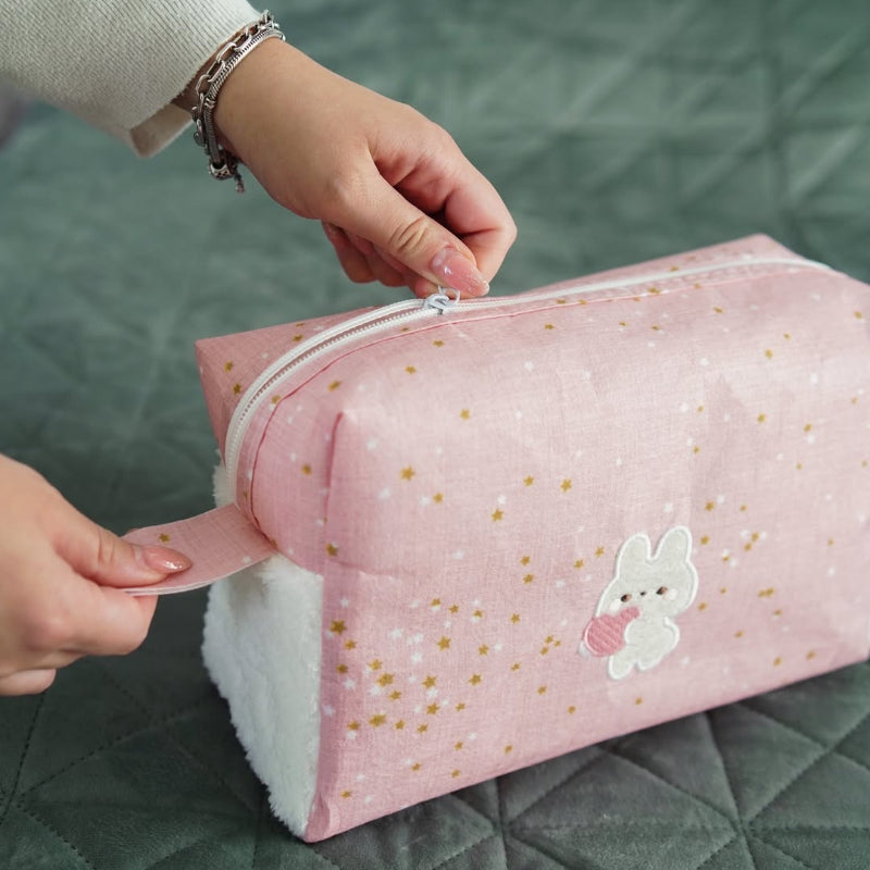 Pink baby nursery organizer set with decorative tissue box cover and zippered storage pouch placed on bed
