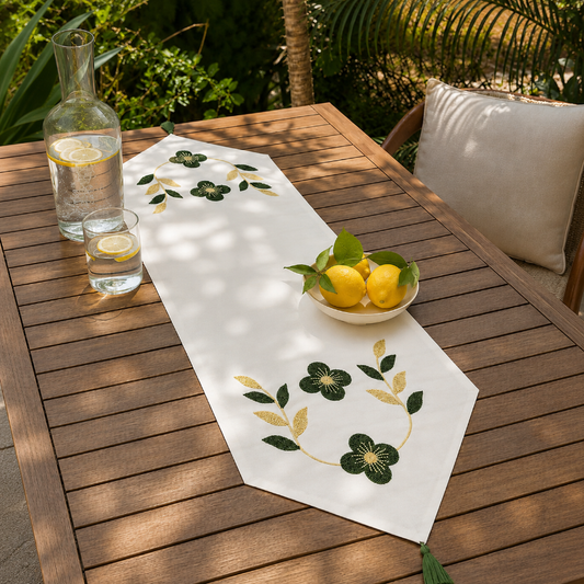 White embroidered table runner with green and gold floral design on wooden coffee table