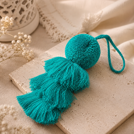 Green fluffy tassel keychain with soft pom pom placed on grass
