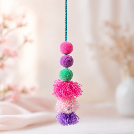 Handmade colorful pom pom tassel hanging decor with bright pom poms and layered yarn tassels on white door background