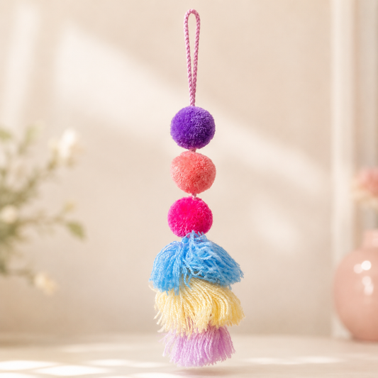 Handmade colorful pom pom tassel hanging decor with vibrant pom poms and layered yarn tassels on white door background
