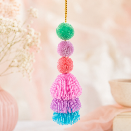 Handmade pastel pom pom tassel hanging decor with soft layered yarn tassels and fluffy pom poms on white door background