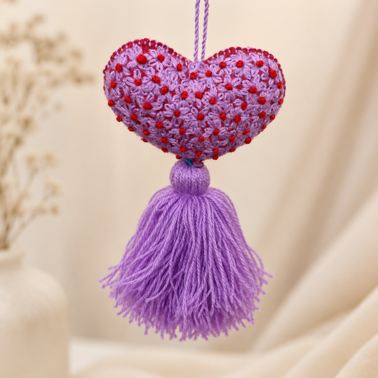 Handmade purple embroidered heart tassel with red floral embroidery and purple yarn fringe on curtain