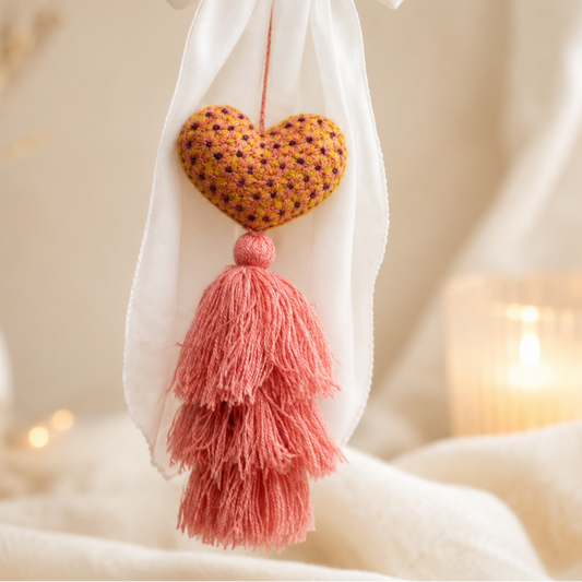 Handmade embroidered heart tassel with pink yarn fringe hanging on curtain