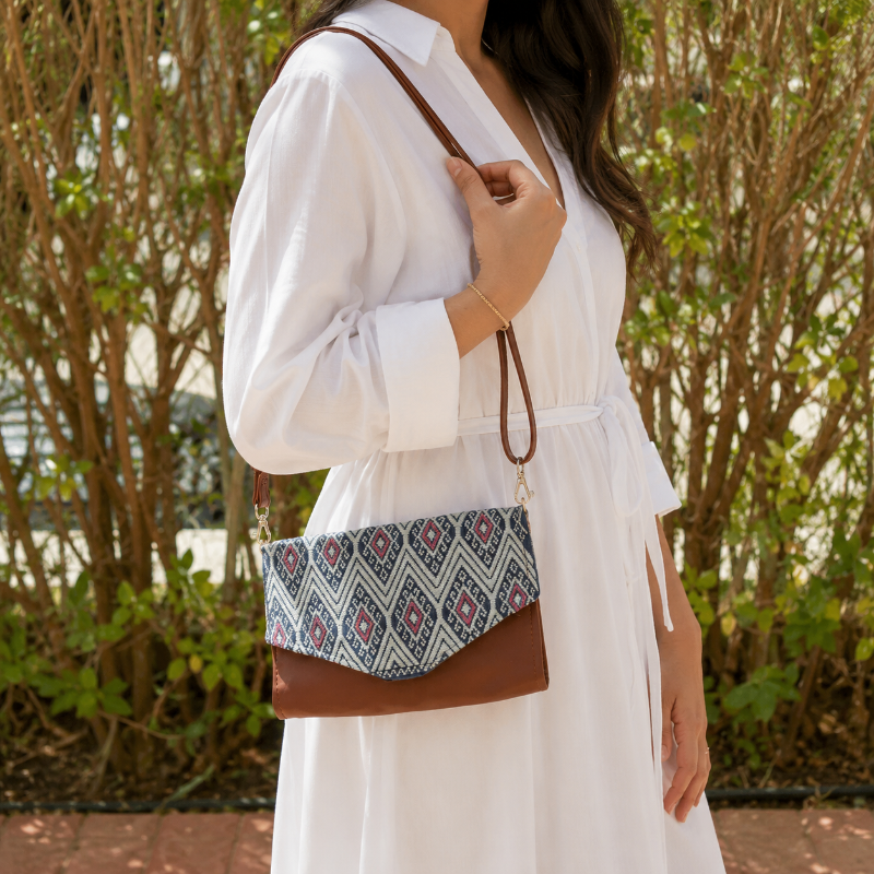 Woman wearing a brown leather crossbody bag with black and grey geometric woven flap outdoors