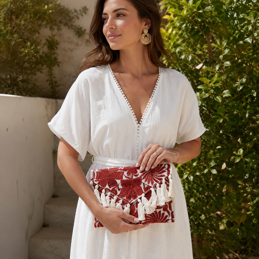 Woman holding a black and white embroidered clutch with tassels in a monochrome boho style outdoors