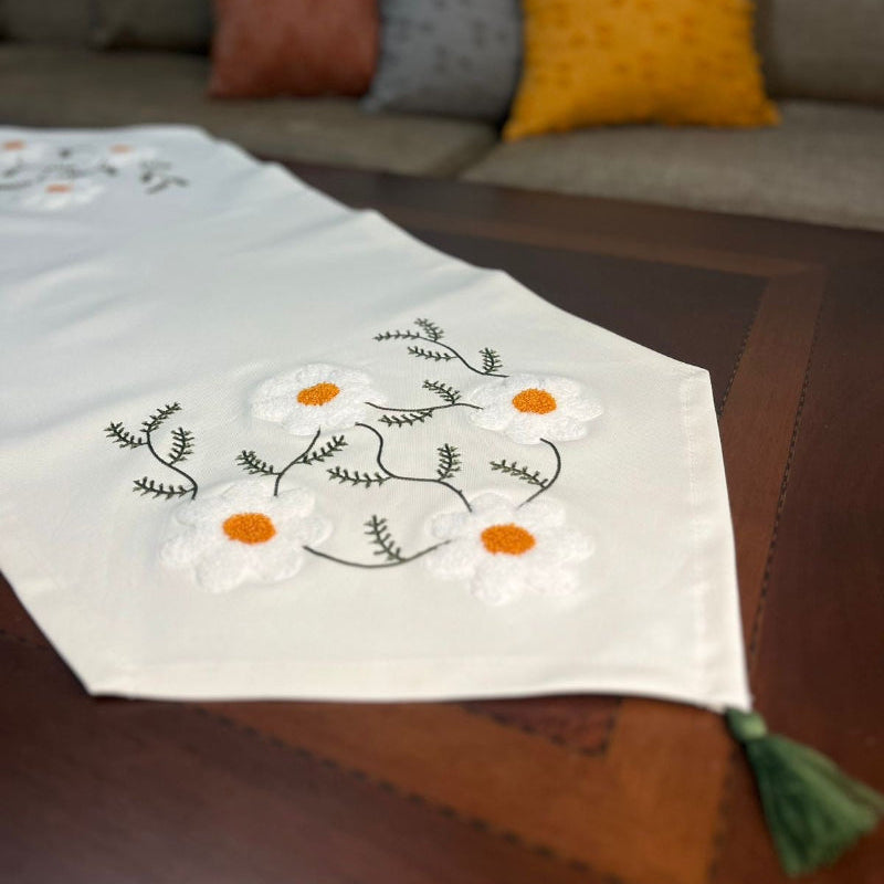 White hand embroidered floral table runner with orange flower details on wooden coffee table