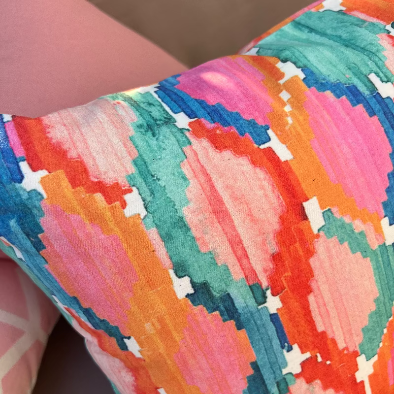 Colorful ikat pattern cushion cover with watercolor geometric design in teal, pink, and orange tones
