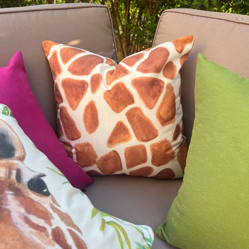 Watercolor giraffe cushion cover with botanical leaves on a decorative white pillow