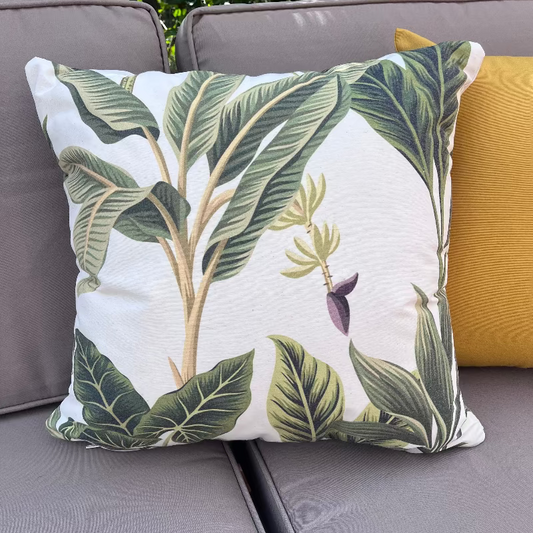 White cushion with green tropical leaves in a botanical pattern design