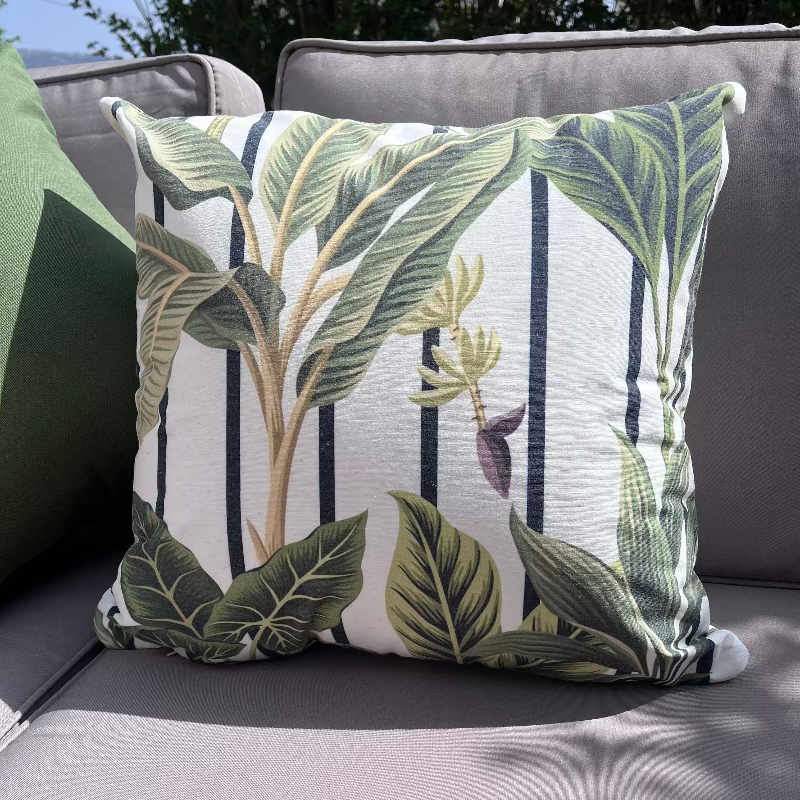 White cushion with green tropical leaves in a botanical pattern design