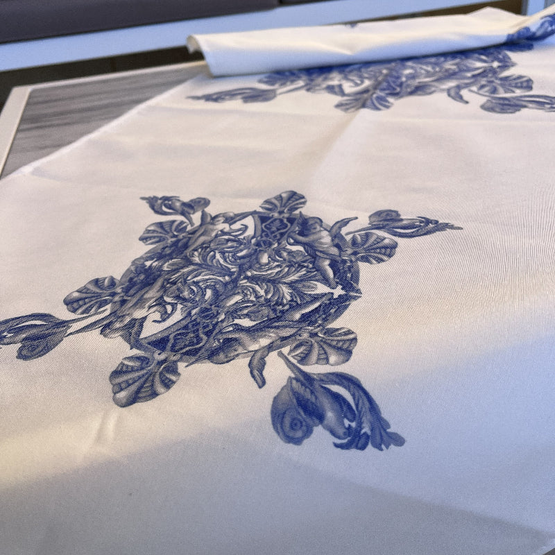 White table runner with blue floral print and blue fringe on a coffee table