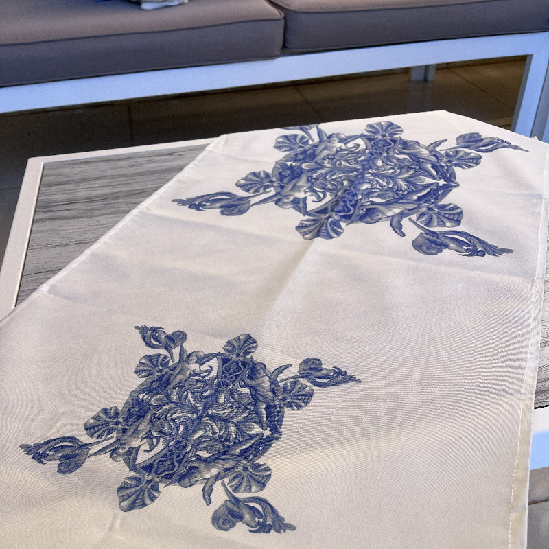 White table runner with blue floral print and blue fringe on a coffee table