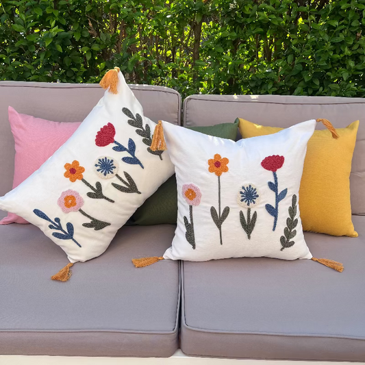 Decorative pillows with floral patterns on a gray sofa outdoors.