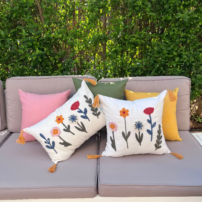 Decorative pillows with floral patterns on a gray sofa outdoors.