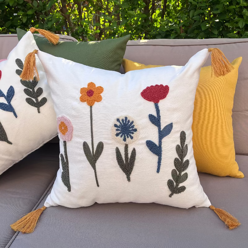 Decorative pillows with floral patterns on a gray sofa outdoors.